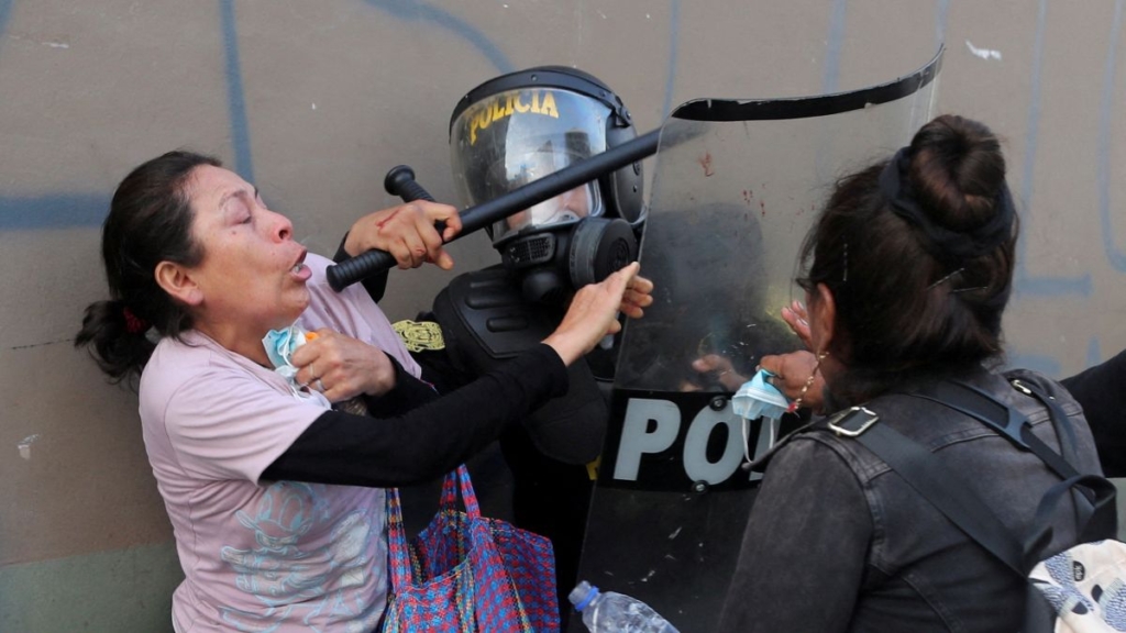 Dos manifestantes se enfrentan a un Policía de Perú que carga con un escudo ensangrentado. Sebastian Castaneda (Reuters).