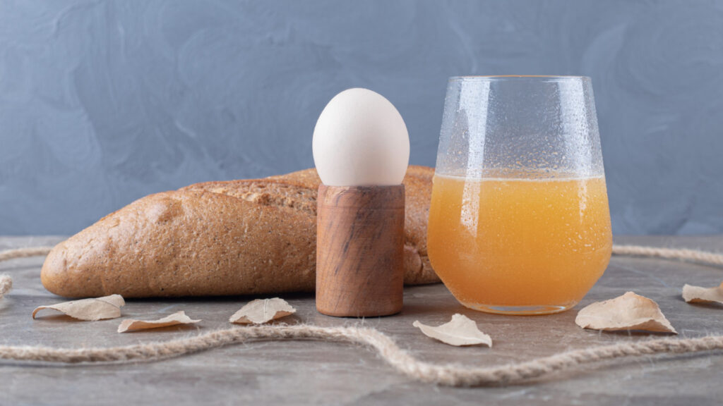 Un huevo cocido, una barra de pan y un zumo de naranja