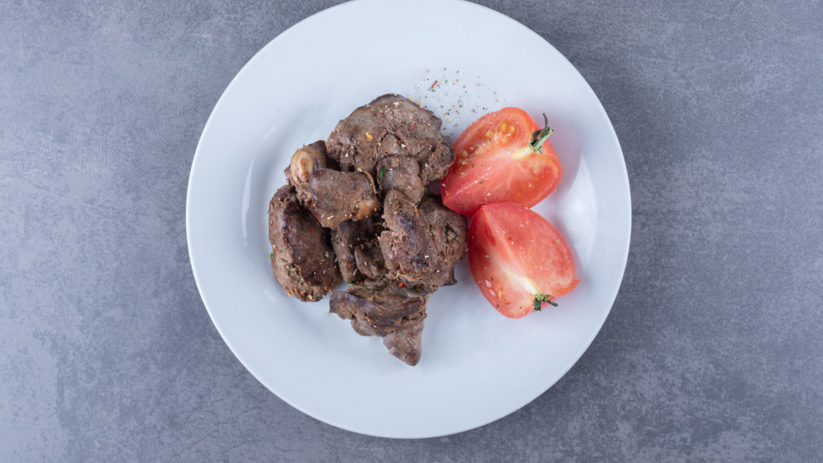 Un plato de hígado de ternera a la plancha con tomate fresco