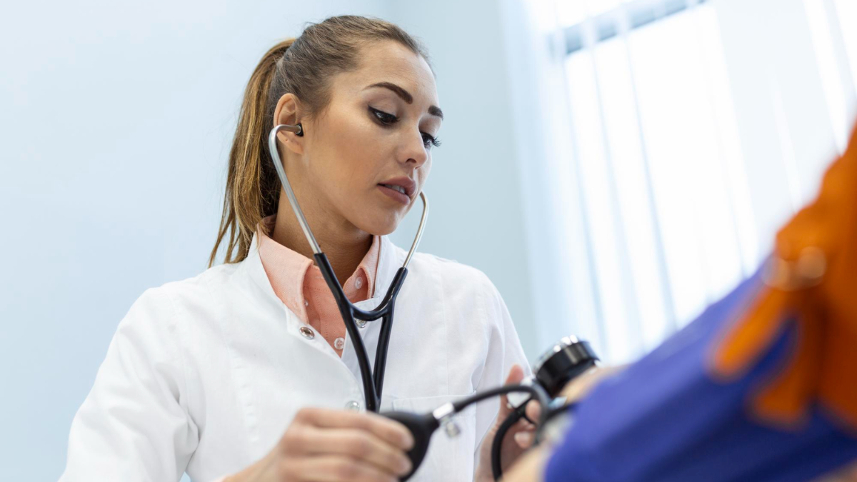 Una doctora toma la presión arterial a un paciente