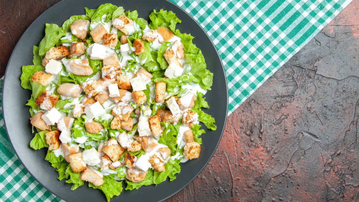 Una ensalada César con pollo asado, picatostes, salsa y lechuga