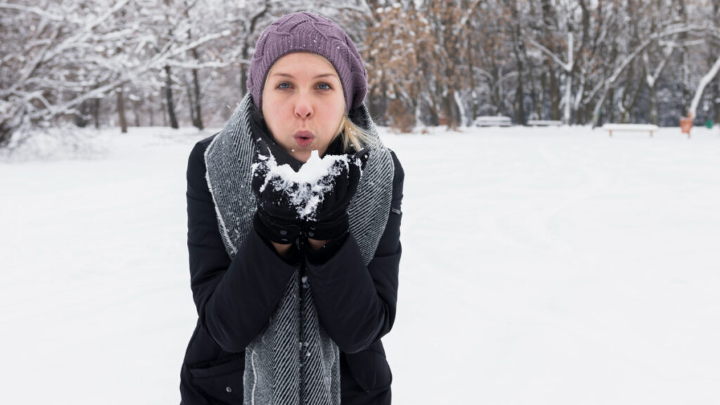 Una mujer pasa frío mientras sujeta nieve en las manos