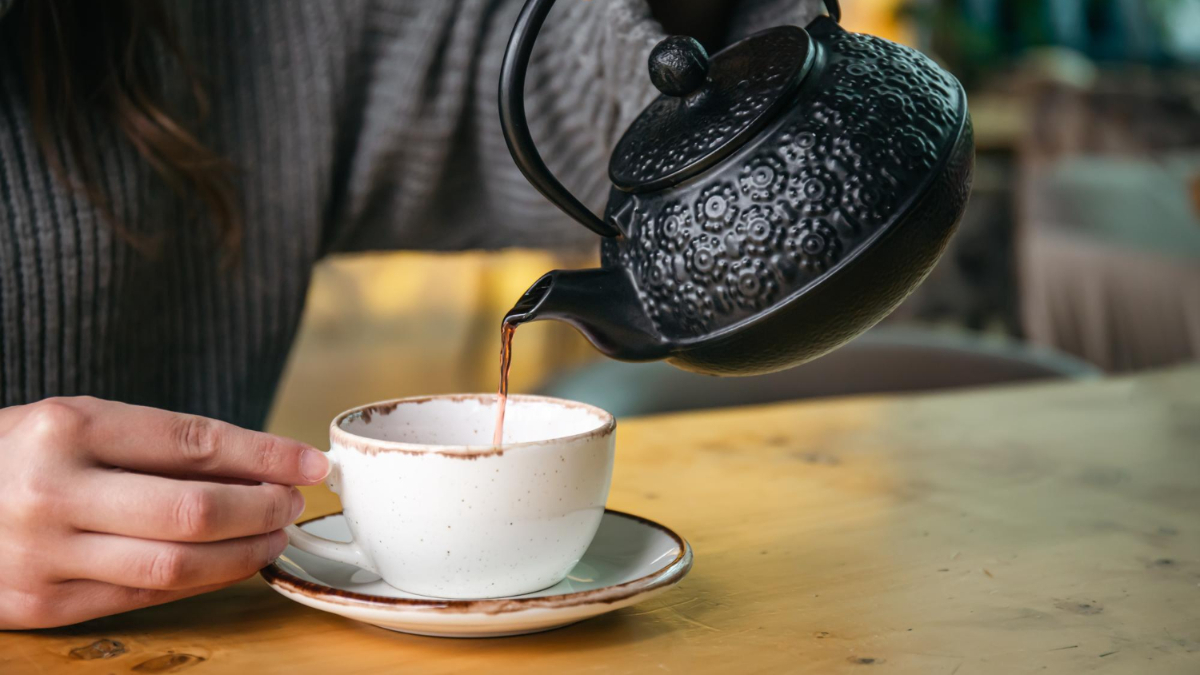 Una mujer sirve un té rojo en una taza