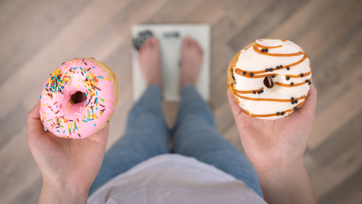 Una mujer sujeta dos rosquillas mientras se pesa en una báscula