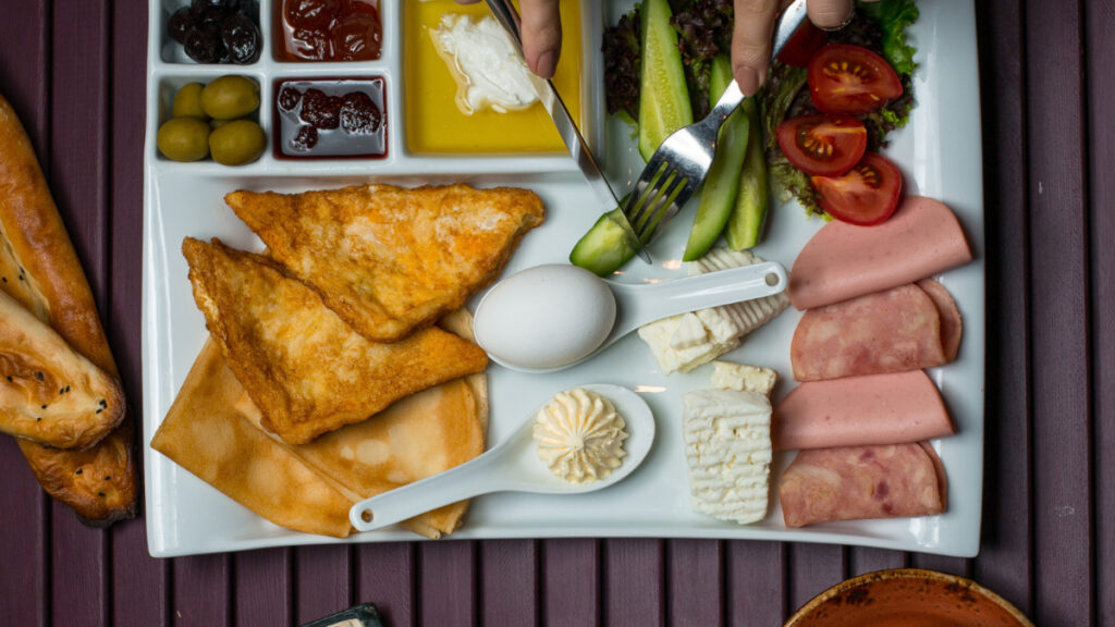 Vista cenital de un desayuno con distintos productos, incluyendo tostadas, queso o fiambre