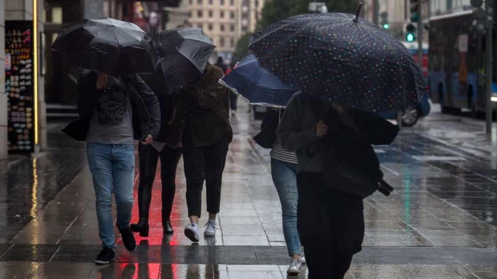 Peresonas andando por la calle con paraguas 