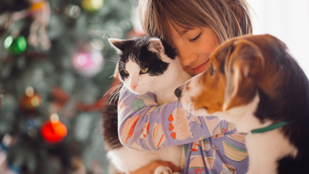 Una niña abraza a varios animales de compañía