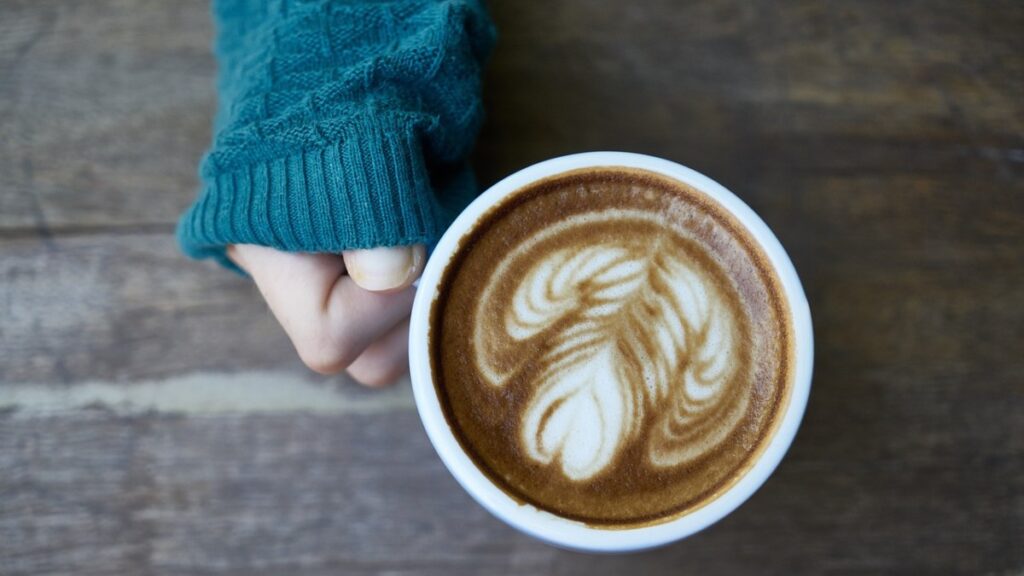Una persona sostiene una taza de café con leche. Foto: Pixabay