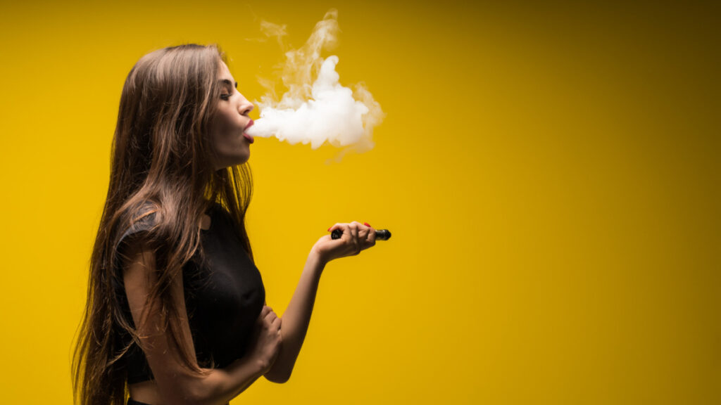 Imagen de una mujer al vapear con un cigarrillo electrónico o vapeador