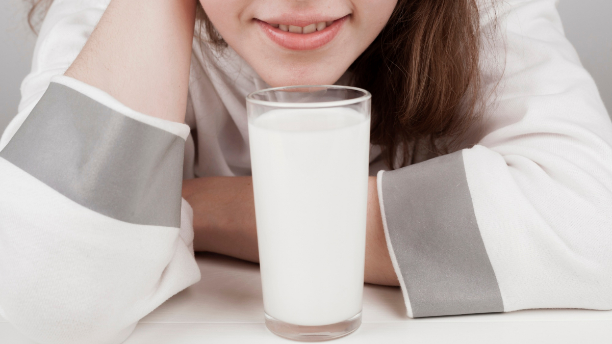 Una mujer con intolerancia a la lactosa frente a un vaso de leche