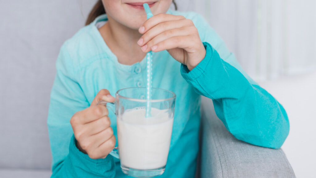 Una niña bebe leche con una pajita