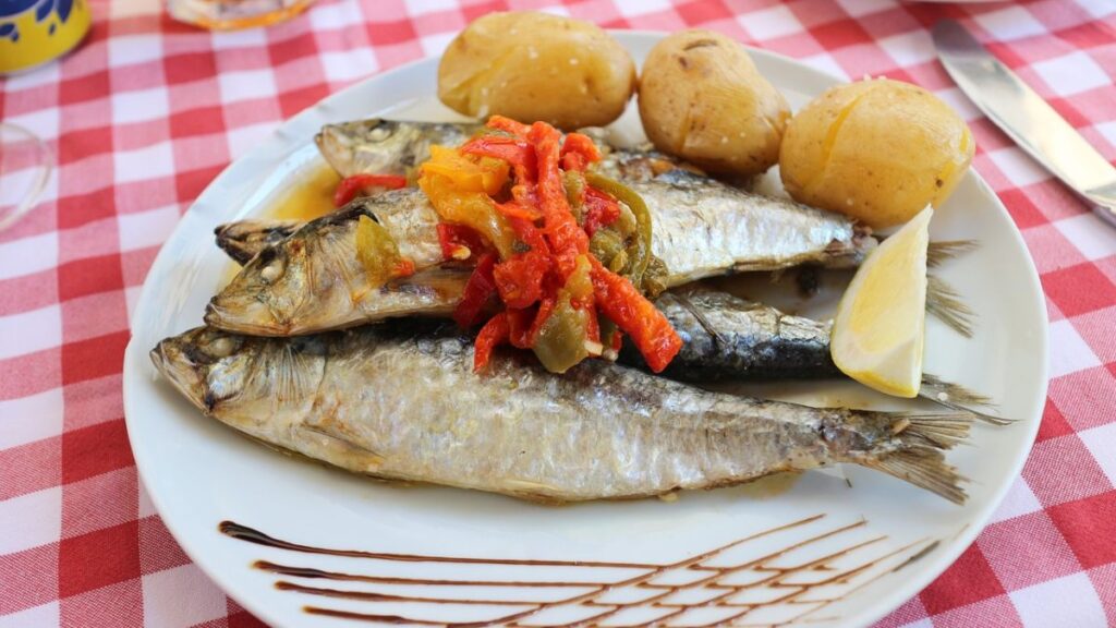 Un plato de sardinas con verduras y patatas. 