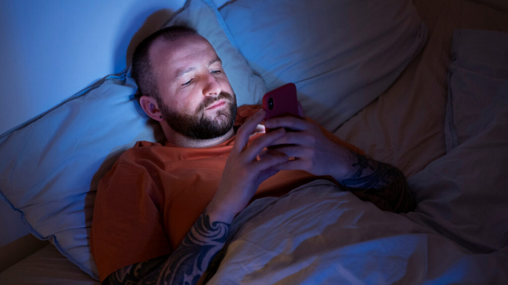 Un hombre utiliza un teléfono a la hora de dormir