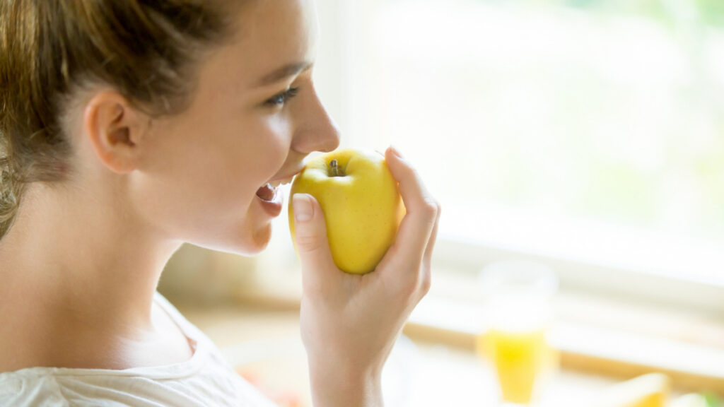 Una mujer secreta saliva al morder una manzana
