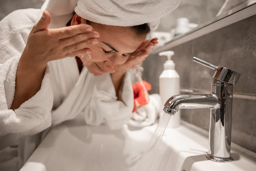 Mujer lavándose la cara con agua. (Fuente: Freepik/pcproductions)