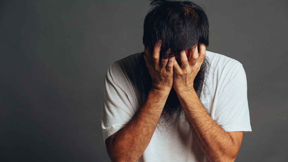 Un hombre catastrofista se tapa la cara