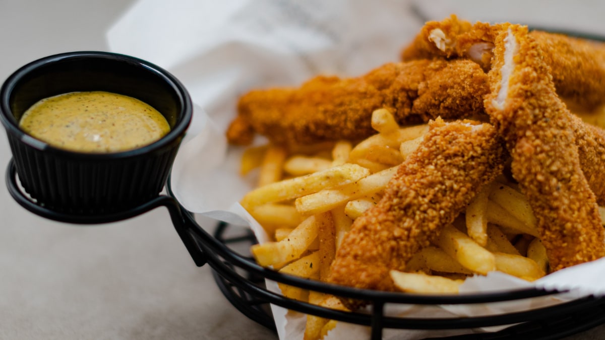 Un plato con patatas fritas y fingers de pollo