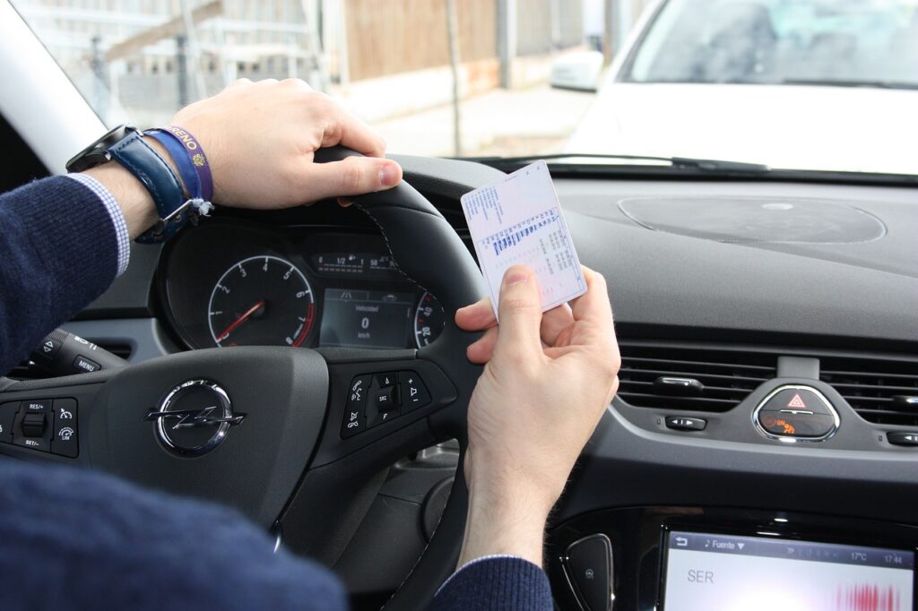Hombre al volante con el carnet de conducir en la mano