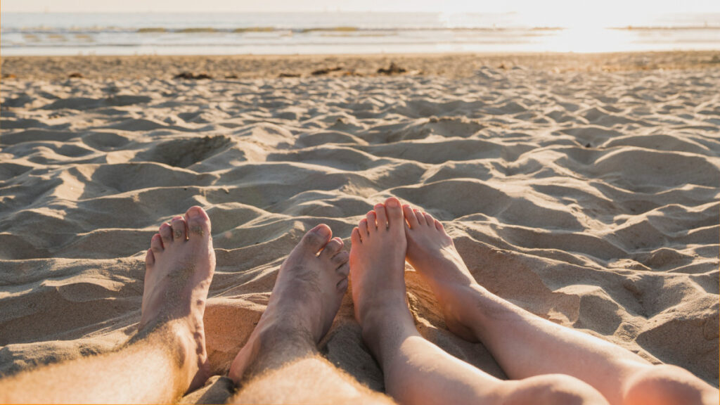 Dos personas con los pies descalzos en la playa