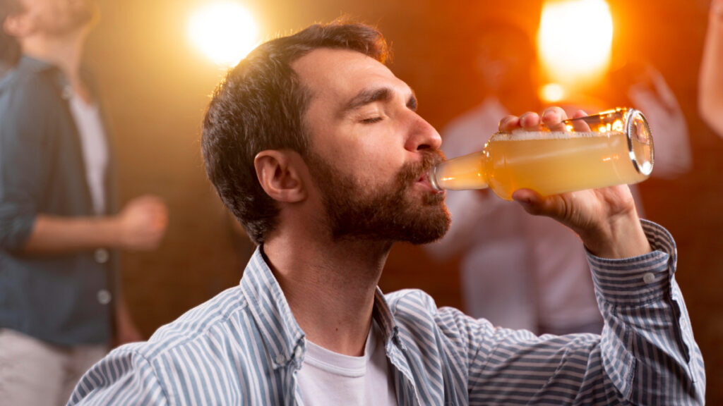 Un hombre bebe una cerveza con alcohol en una discoteca