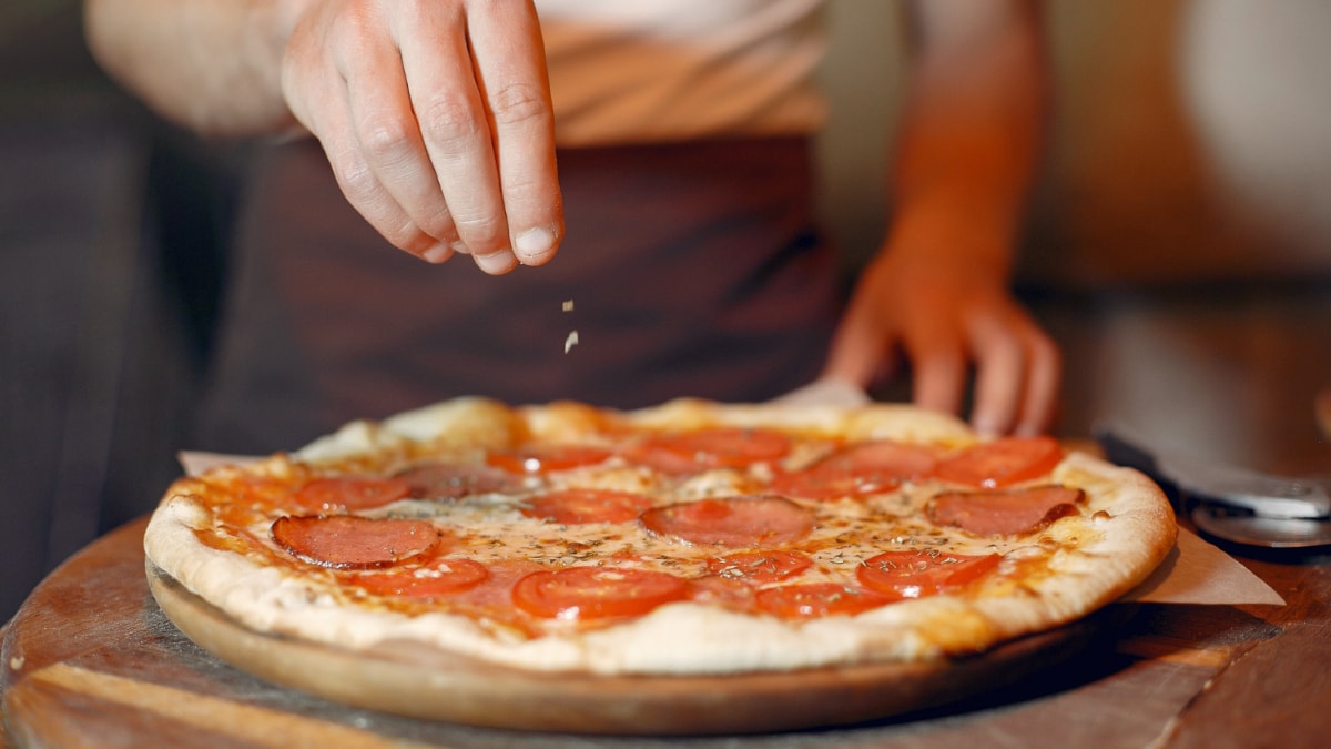 Un pizzero termina una pizza de pepperoni