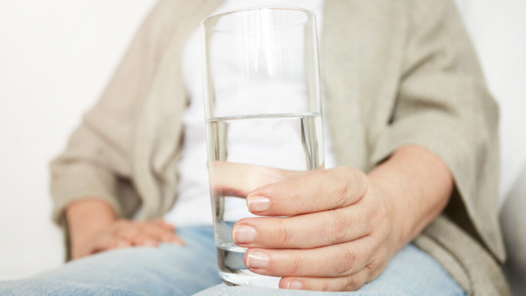 Una mujer sujeta un vaso de agua alcalina