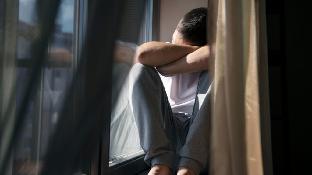 Un hombre con depresión en verano en la ventana.
