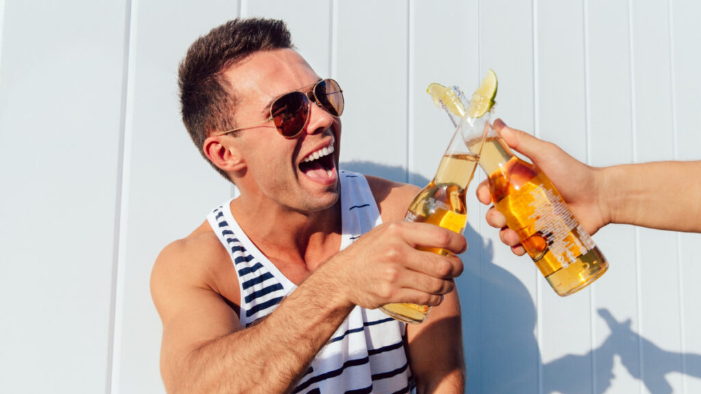 Un hombre joven brinda con una cerveza en verano