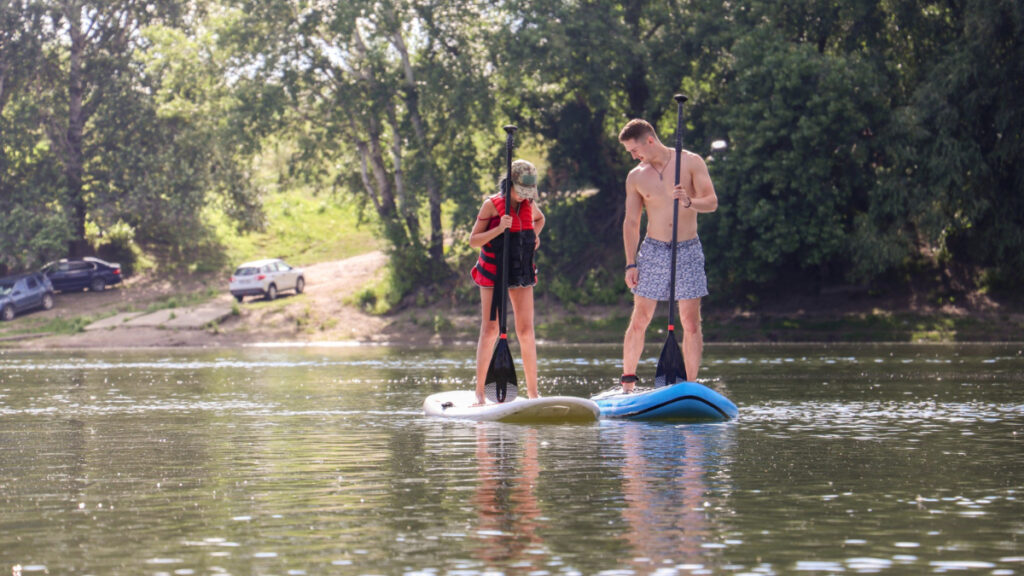 Un hombre y una mujer hacen paddle surf en un río