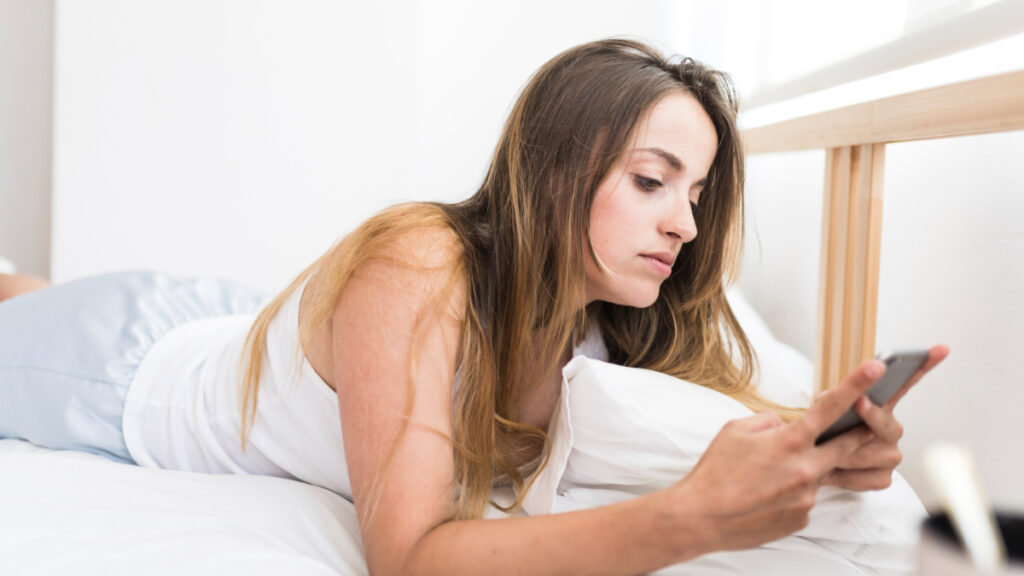 Una mujer usa el teléfono en la cama