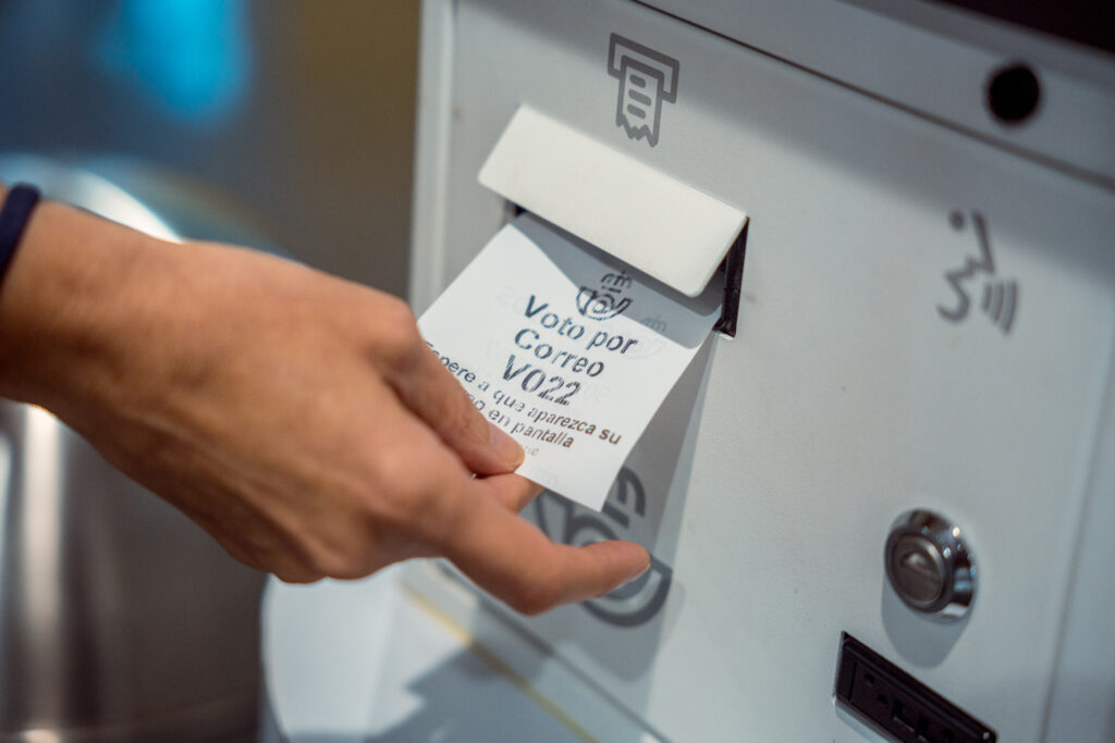 Una persona recoge el ticket para solicitar el voto por correo en el Edificio de correos, a 14 de junio de 2023, en Madrid.