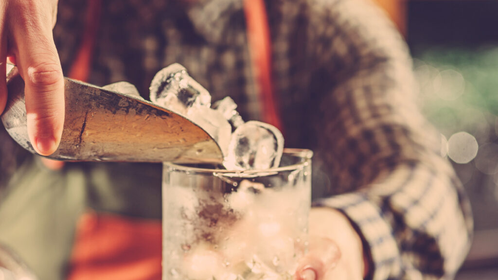 Un camarero echa hielos en un vaso