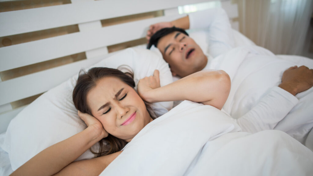 Una mujer se tapa los oídos mientras su pareja empieza a roncar