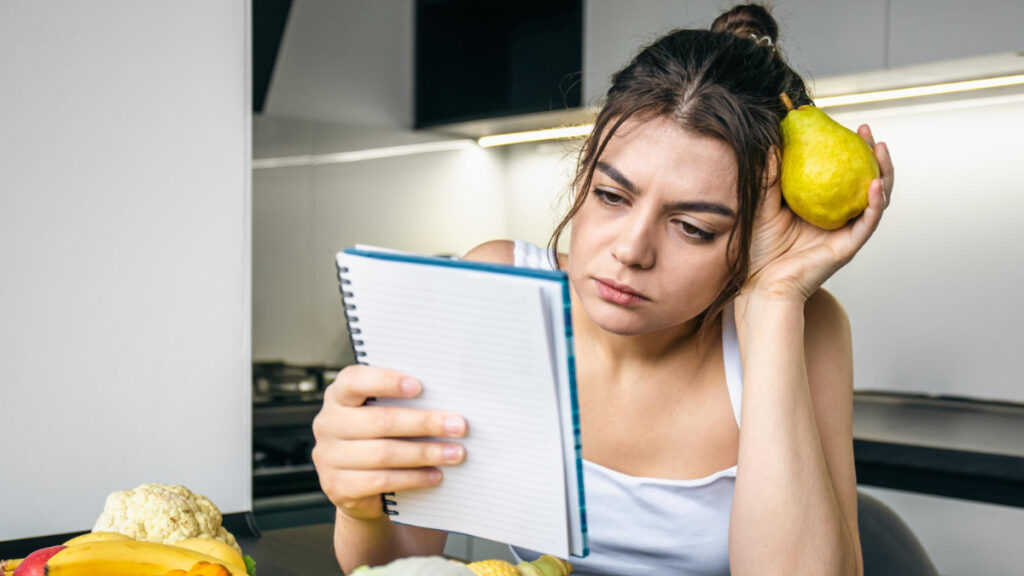 Una mujer cansada con un cuaderno en la cocina