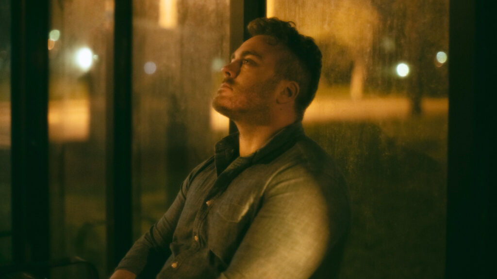 Un hombre sentado de noche en una parada de autobús