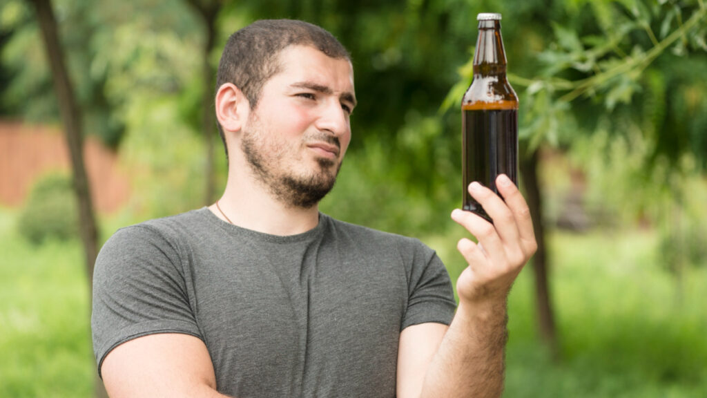 Un hombre pensativo sujeta una botella de cerveza