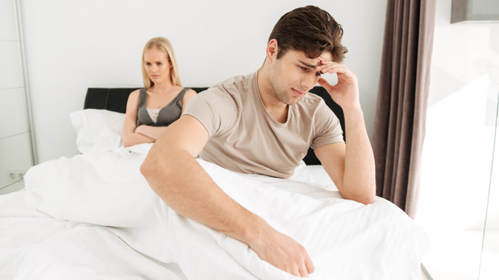 Un hombre preocupado en la cama con su pareja