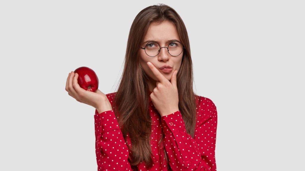 Una mujer sostiene una manzana mientras piensa