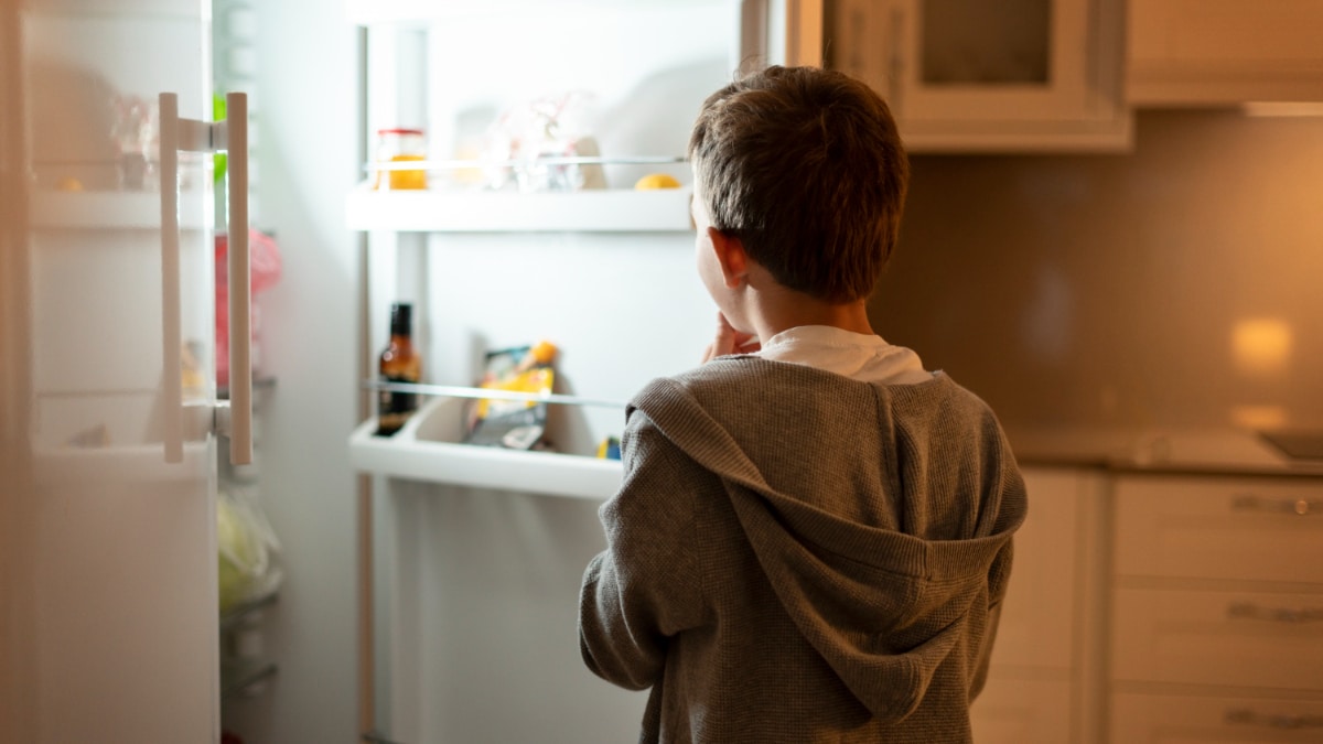 Un niño abre la nevera por la noche