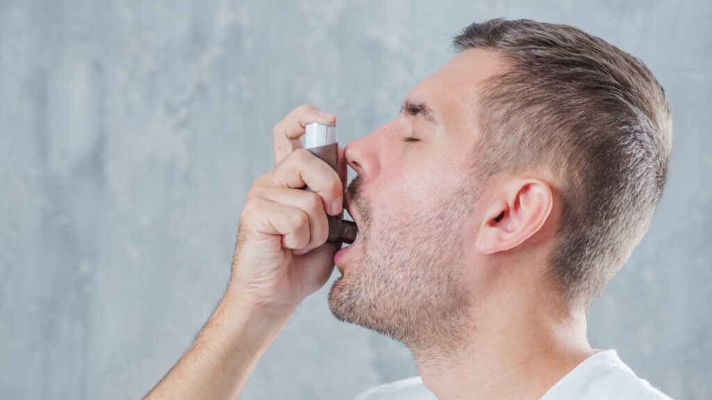 Un hombre con asma alérgica recurre a un broncodilatador