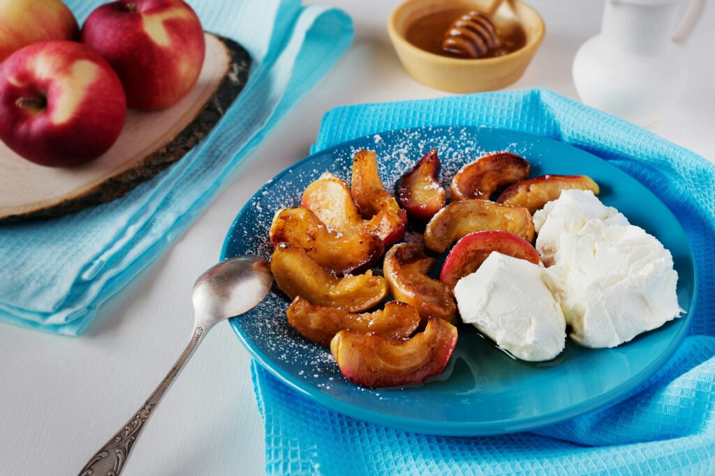 Presentación de las manzanas asadas en lonchas y acompañadas de nata. Elena Leya, Unsplash