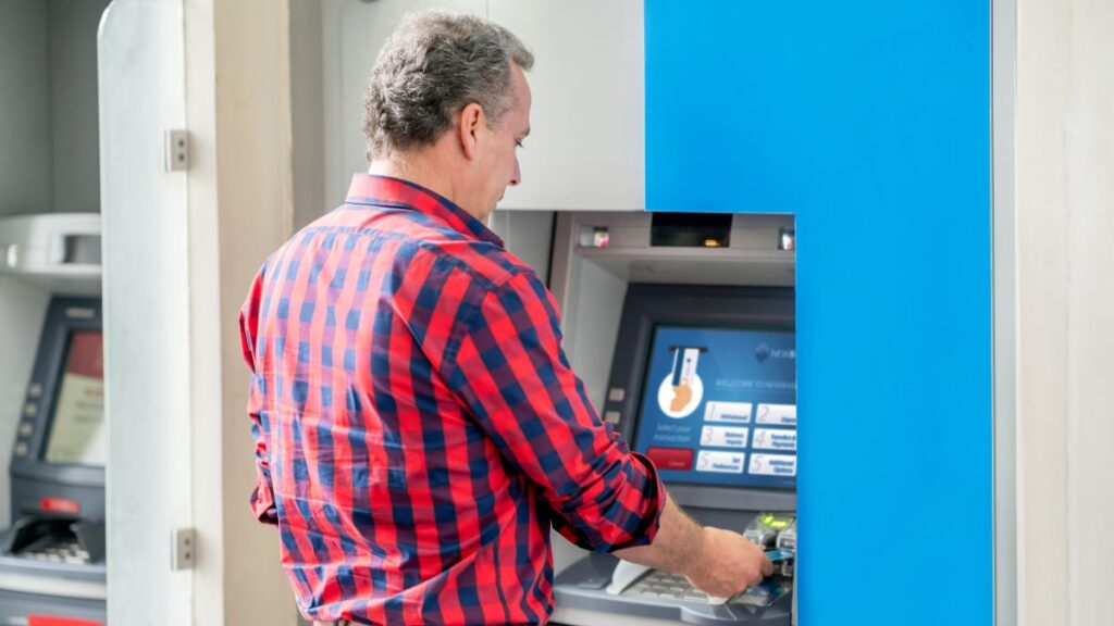 Pensionista extrayendo dinero de un cajero: (Canva)