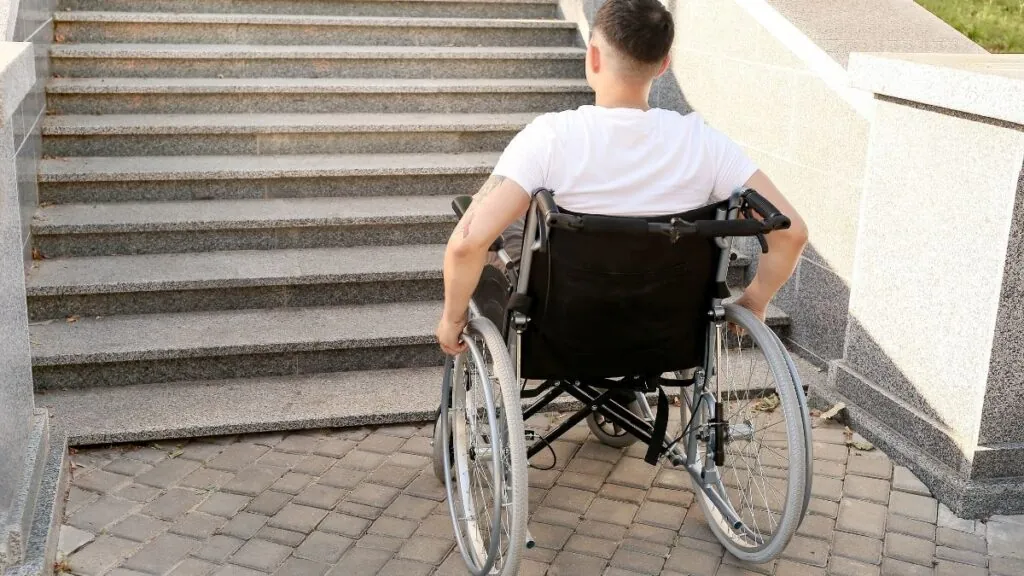 Chico en silla de ruedas frente a una barrera arquitectónica. Canva