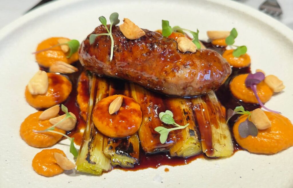 Plato de calçots confitados a baja temperatura con butifarra de perol y salsa romesco en el restaurante Barra Alta, Madrid.