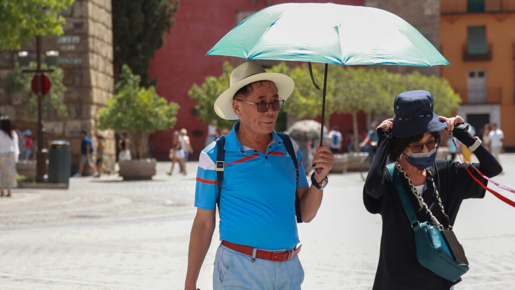 Varios turistas se resguardan del sol con sombreros y paraguas para soportar las altas temperaturas en Sevilla.