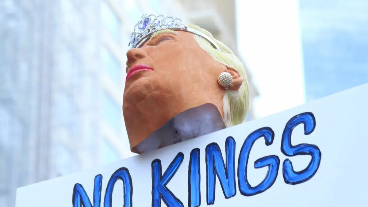 Una efigie de Donald Trump sobre una estaca. Está hecha con una máscara de goma. Debajo de ella, se ve una pancarta que reza "No kings", "nada de reyes"