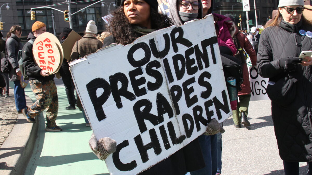 Una mujer sujeta una pancarta que reza: "Nuestro presidente viola niños"