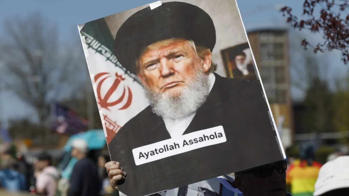 Una pancarta en la que se ve una efigie de Trump vestido como un ayatolá, con barba gris y turbante y túnica negros. Debajo de él, se ve un texto que reza "ayatolá gilipollá"